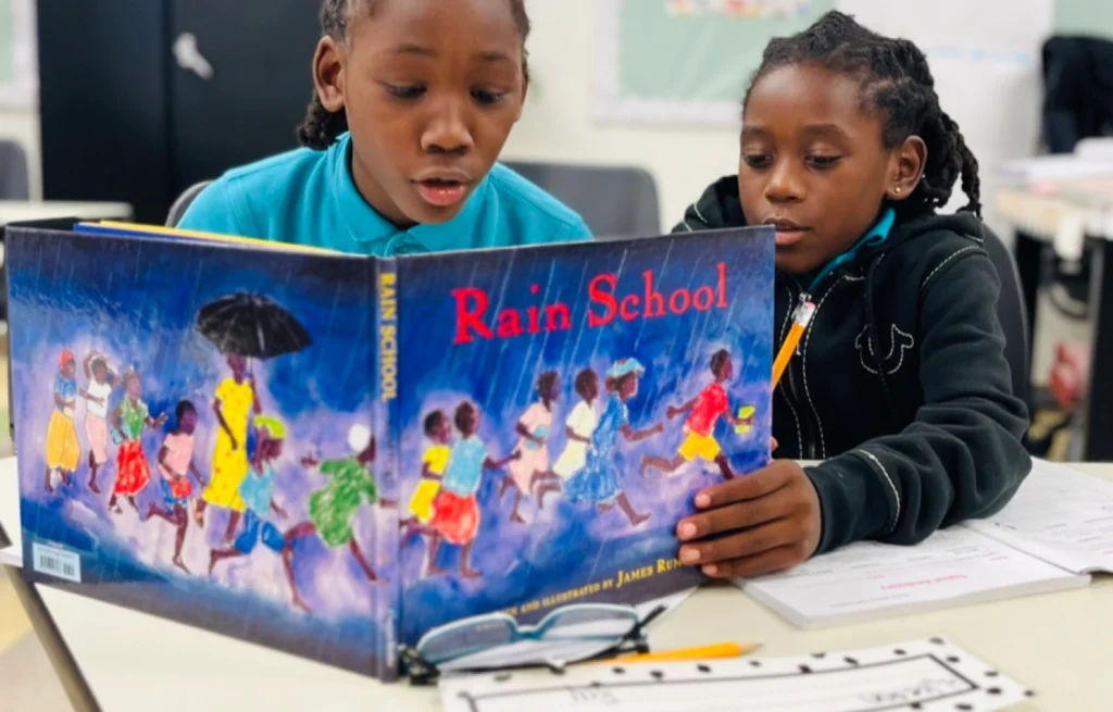 Two kids reading a book titled 'Rain School'.