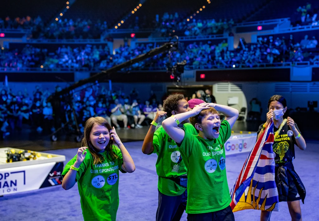Kids smiling and being excited in front od a crowd.